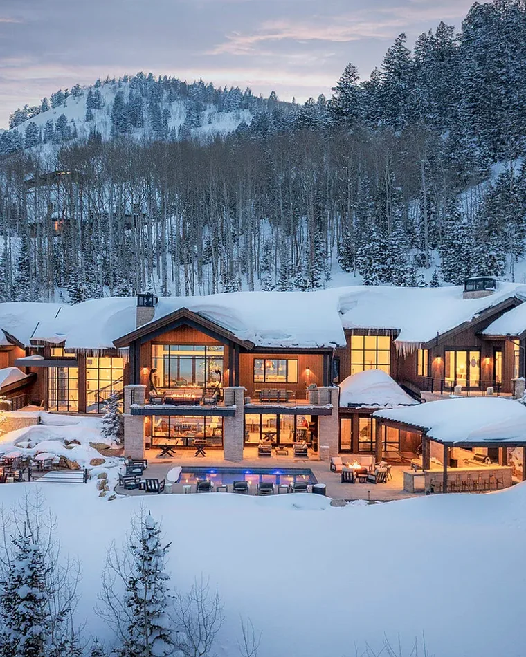 Timber and stone estate glowing at dusk in deep snow